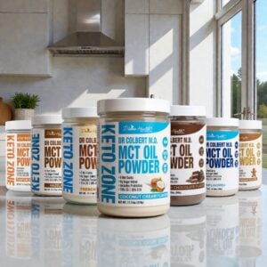 Divine Health Dr. Don Colbert, MD MCT Oil Powder flavor collection arranged on a polished kitchen countertop, featuring multiple jars in a lineup: Coconut Cream centered in front, surrounded by flavors including Hazelnut, Unflavored, Vanilla, Gingerbread, Pumpkin Spice, Dutch Chocolate, and French Vanilla. Each container displays bold Keto Zone branding, flavor-specific colors, and clean white lids, set against a modern kitchen backdrop with stainless-steel appliances, bright window light, and neutral cabinetry.