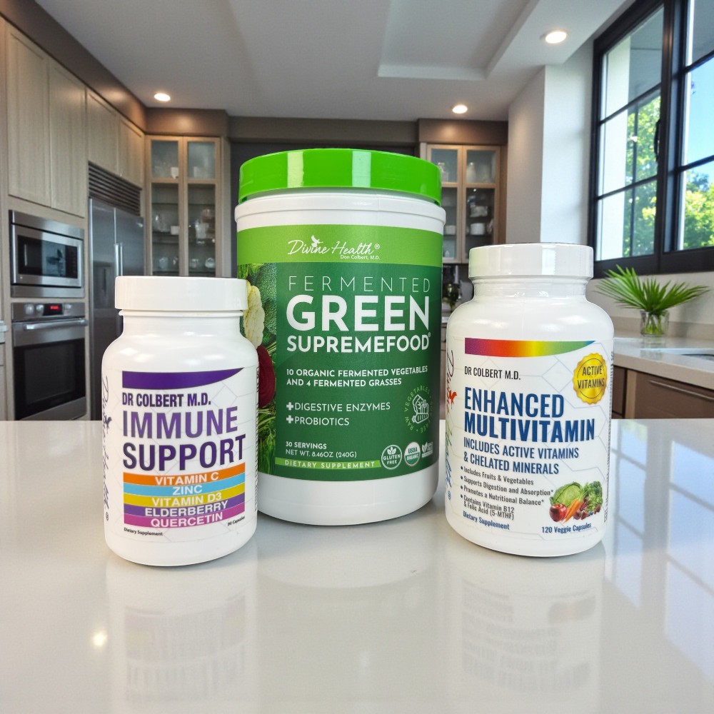 Divine Health Dr. Don Colbert, MD Immune Support Maintenance Pack displayed on a polished kitchen counter, featuring three products: Immune Support with a white and purple label, Fermented Green Supremefood with a tall green container, and Enhanced Multivitamin with a white label and rainbow accent; all set against a modern kitchen backdrop with natural window light, cabinets, and stainless-steel appliances.