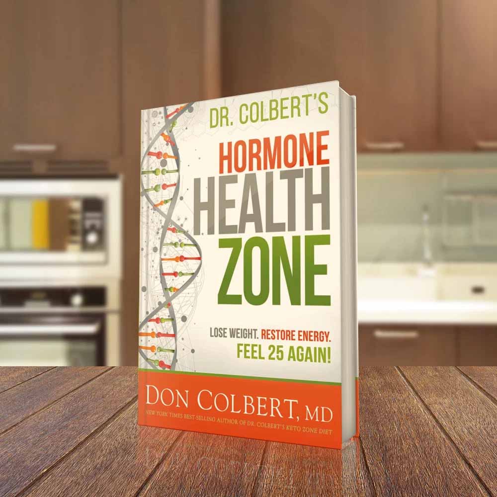 Dr. Colbert’s Hormone Health Zone book by Dr. Don Colbert, MD from Divine Health displayed standing on a wooden table in a modern kitchen setting. The book focuses on hormone balance, metabolism, and energy while discussing how nutrition, probiotics, fiber supplements, collagen-supporting nutrients, and healthy fats like MCT oil powder may help support hormonal wellness and overall health.