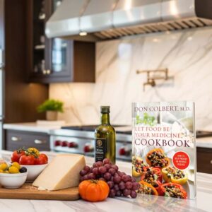 Dr. Colbert’s Let Food Be Your Medicine Cookbook hardcover by Dr. Don Colbert, MD from Divine Health displayed on a modern kitchen countertop beside fresh vegetables, olive oil, cheese, and fruit. The cookbook promotes nutrition-focused recipes designed to support gut health, digestion, and overall wellness through whole foods rich in fiber, probiotics, healthy fats, and nutrient-dense ingredients that complement collagen powder, fiber supplements, and MCT oil powder nutrition strategies.