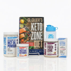 A Keto Zone Starter Pack displayed on a white background, featuring Dr. Colbert’s Keto Zone Diet book standing in the center. In front and beside the book are several Keto Zone products, including MCT Oil Powder in a white jar, Instant Ketones powder in a small container, Fiber Zone Gut Health powder in a larger jar, a box of Ketone Test Strips, and a blue Keto Zone shaker bottle. All items are arranged neatly with clear labels and Divine Health branding by Dr. Don Colbert, MD.