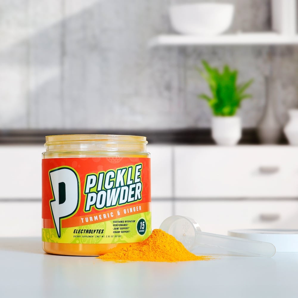 Divine Health Pickle Powder by Dr. Colbert on a kitchen counter with a scoop and bright orange powder supports hydration joint health and muscle recovery with electrolytes and antioxidant ingredients