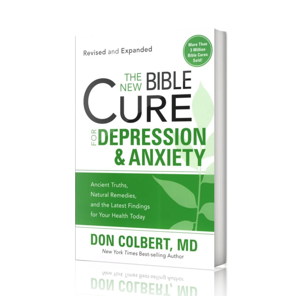 A revised and expanded softcover book titled “The New Bible Cure for Depression & Anxiety” by Don Colbert, MD is displayed standing upright on a glossy white surface against a clean white background. The book is angled slightly to the right, revealing the softcover binding and page thickness. The cover features a green and white color palette with a large leaf graphic, bold title text, and a circular green badge reading “More Than 3 Million Bible Cures Sold.” The minimalist presentation emphasizes clarity, calmness, and emotional wellness, with even lighting and no additional props in the scene.
