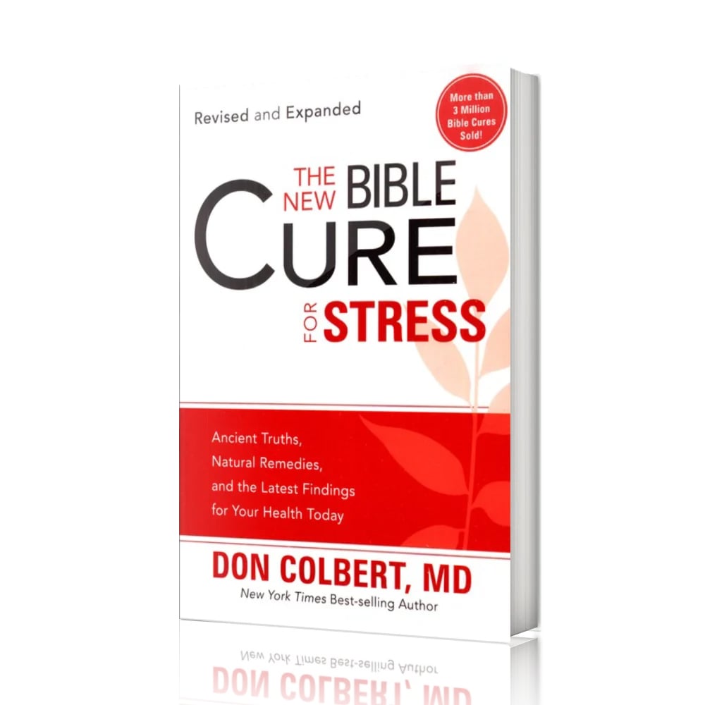 A softcover paperback book titled “The New Bible Cure for Stress” by Don Colbert, MD is shown standing upright against a clean white background. The book is slightly angled to the right, revealing the thickness of the pages and the spine. The cover design features a white upper section with bold black and red typography, with the word “CURE” prominently centered and “Stress” printed below in red capital letters. A red horizontal band spans the lower portion of the cover, accented by a subtle leaf graphic. Near the top right corner of the cover, a circular red badge reads “More than 3 Million Bible Cures Sold,” while light gray text above the title states “Revised and Expanded.” The minimalist presentation places full emphasis on the book itself, highlighting its professional design, soft matte finish, and clear visual hierarchy without additional props or background elements.