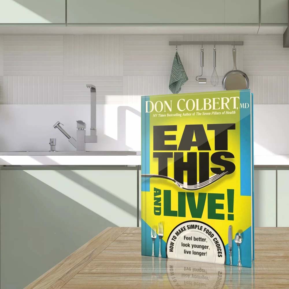 Eat This and Live: Simple Food Choices That Can Help You Feel Better, Look Younger, and Live Longer! by Dr. Don Colbert, MD from Divine Health displayed on a modern kitchen countertop. The nutrition and wellness book focuses on improving health through better dietary choices that support gut health, digestion, and metabolic balance. It highlights how nutrient-rich foods, probiotics, fiber intake, collagen-supporting nutrition, and healthy fats such as those used in ketogenic-style nutrition with MCT oil powder can contribute to improved energy, digestion, and long-term wellness.