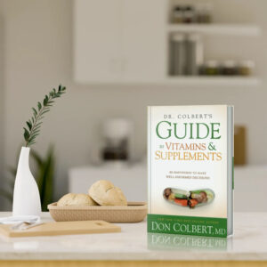 Dr. Colbert’s Guide to Vitamins and Supplements book by Dr. Don Colbert, MD from Divine Health displayed standing on a modern kitchen countertop beside fresh bread and a plant. The book focuses on helping readers understand vitamins, probiotics, collagen-supporting nutrients, and fiber supplements while explaining how proper supplementation can support gut health, immune function, metabolism, and overall wellness.