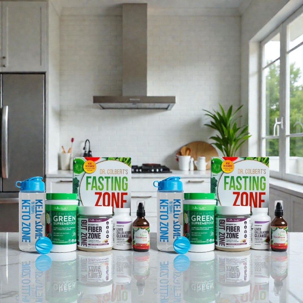 Divine Health Dr. Don Colbert, MD Couples Detox Starter Pack arranged symmetrically on a polished kitchen countertop, featuring two identical detox sets: each including a bright blue Keto Zone shaker bottle with mixing ball, a Fermented Green Supremefood container, a Fiber Zone tub, a Liver Gallbladder Cleanse bottle, a Nano Glutathione dropper bottle, and Dr. Colbert’s “Fasting Zone” book standing upright behind the products. The setup is displayed in a modern kitchen with stainless-steel appliances, white cabinetry, large windows, and natural lighting.