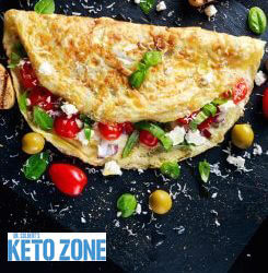 Mediterranean keto omelette with feta, olives, cherry tomatoes and fresh basil on a white plate