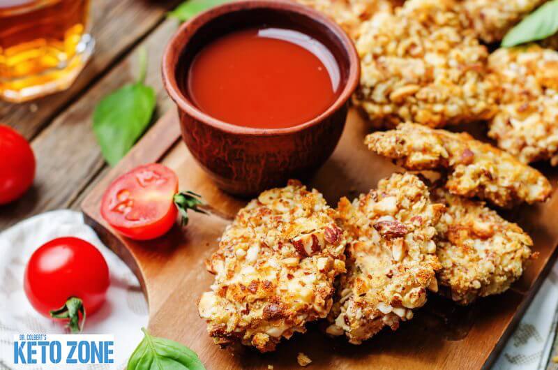 Crispy keto chicken tenders with a low carb coating on a serving board