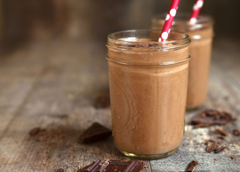 Thick chocolate avocado smoothie in a glass with a straw