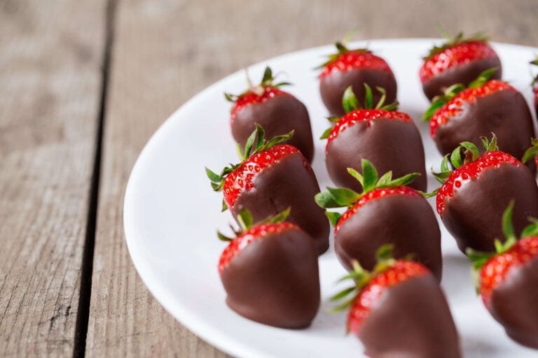 Keto chocolate covered strawberries on parchment, a sugar free low carb dessert dipped in cacao and coconut oil