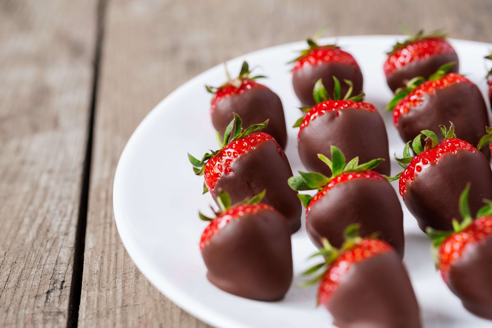 Keto chocolate covered strawberries on parchment, a sugar free low carb dessert dipped in cacao and coconut oil