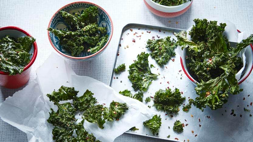 Crispy keto kale chips on a baking tray, a salty low carb vegan snack
